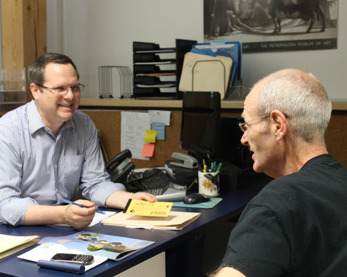 Staff member smiling at client from behind desk